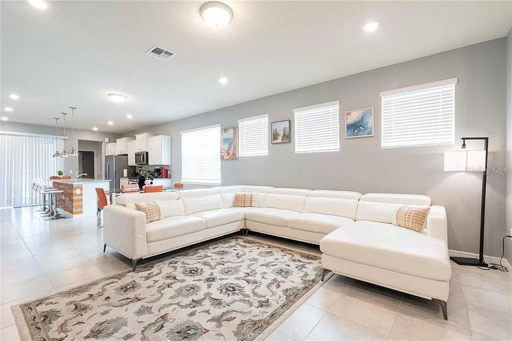 A white sectional sofa sits on a patterned rug in a bright, open-concept living room — 7243 OAKMOSS LOOP, DAVENPORT, FL