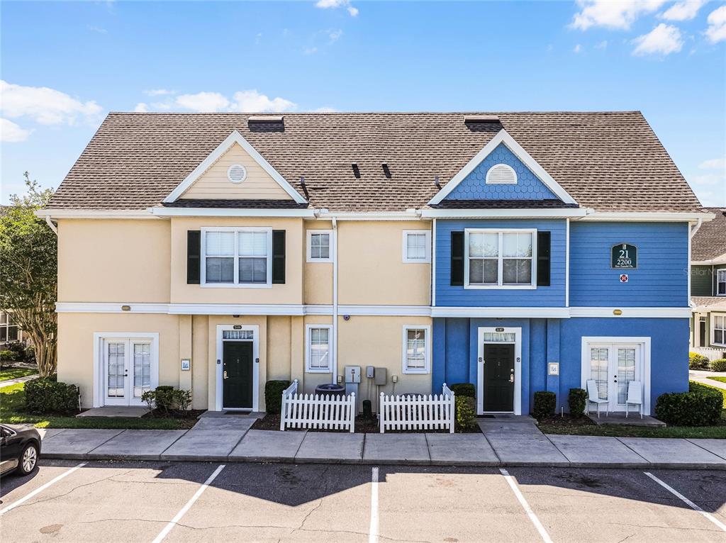 A two-story duplex building features yellow and blue siding with white trim and small fences — 2200 SAN ZANOBI DRIVE UNIT 108, KISSIMMEE, FL
