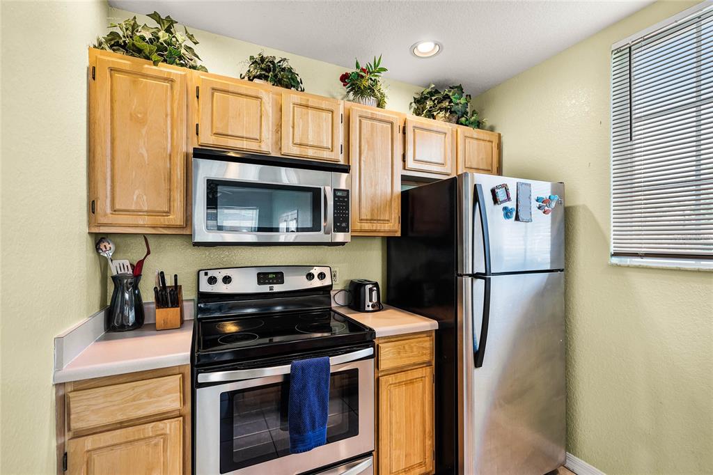 A kitchen features light wood cabinets, stainless steel appliances, and a black electric range — 2200 SAN ZANOBI DRIVE UNIT 108, KISSIMMEE, FL