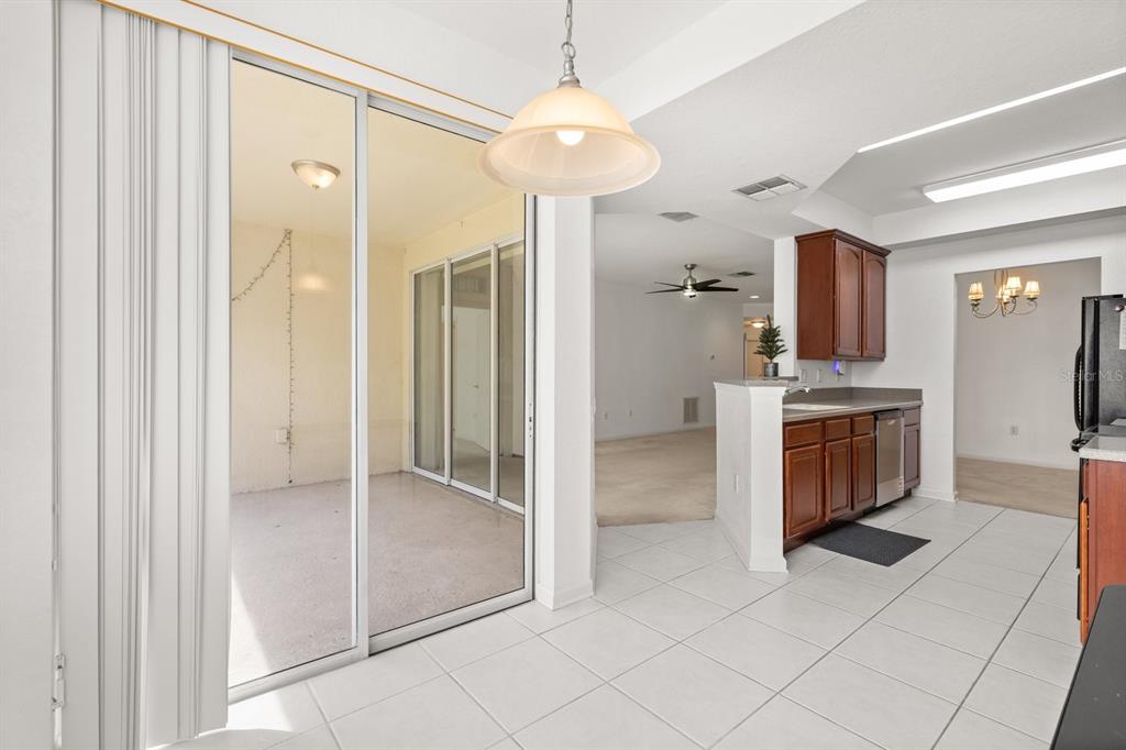 A kitchen with white tile floors and dark wood cabinets overlooks a screened-in patio — 409 HILGARD COVE UNIT 106, SANFORD, FL