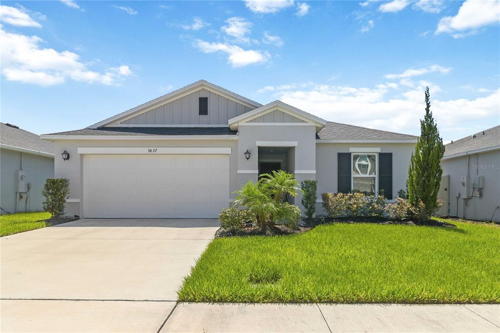 A single-story house with a two-car garage, gray stucco siding, and a front lawn — 3837 ELK BLUFF ROAD, ST CLOUD, FL
