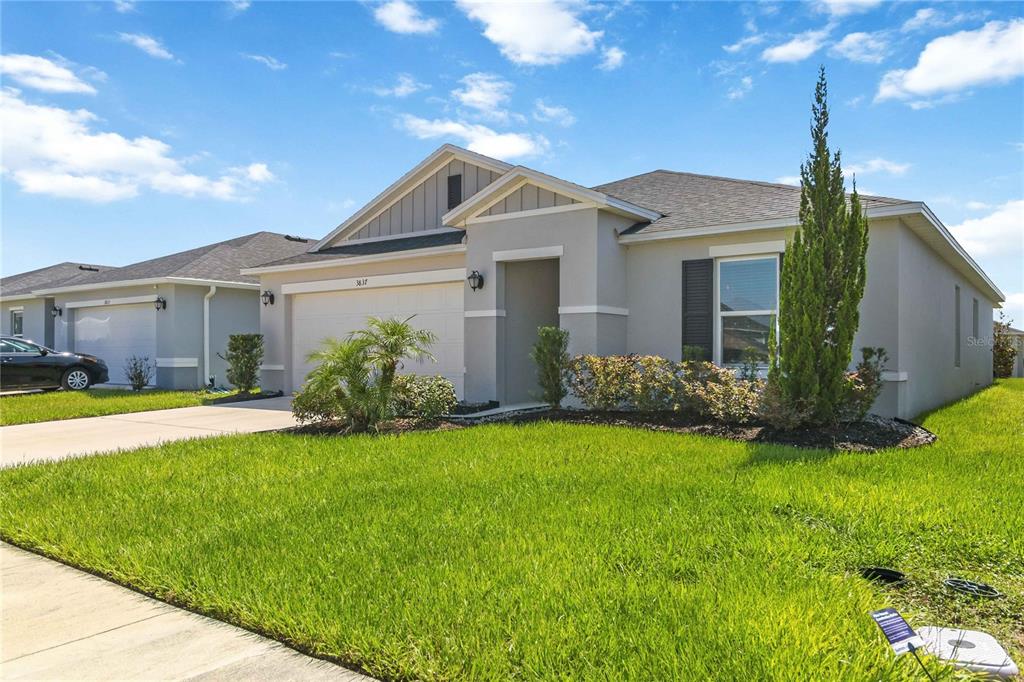 A single-story suburban house with a two-car garage, light gray siding, and a manicured lawn — 3837 ELK BLUFF ROAD, ST CLOUD, FL
