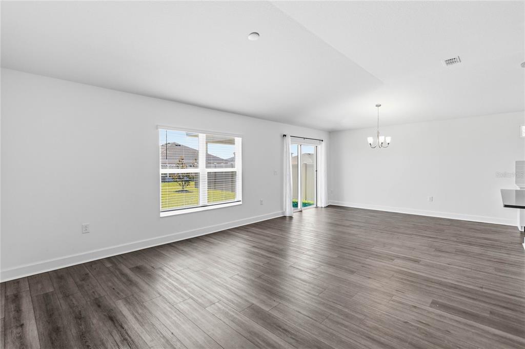 An empty room with gray wood-look flooring, white walls, a window, and sliding glass doors — 3837 ELK BLUFF ROAD, ST CLOUD, FL