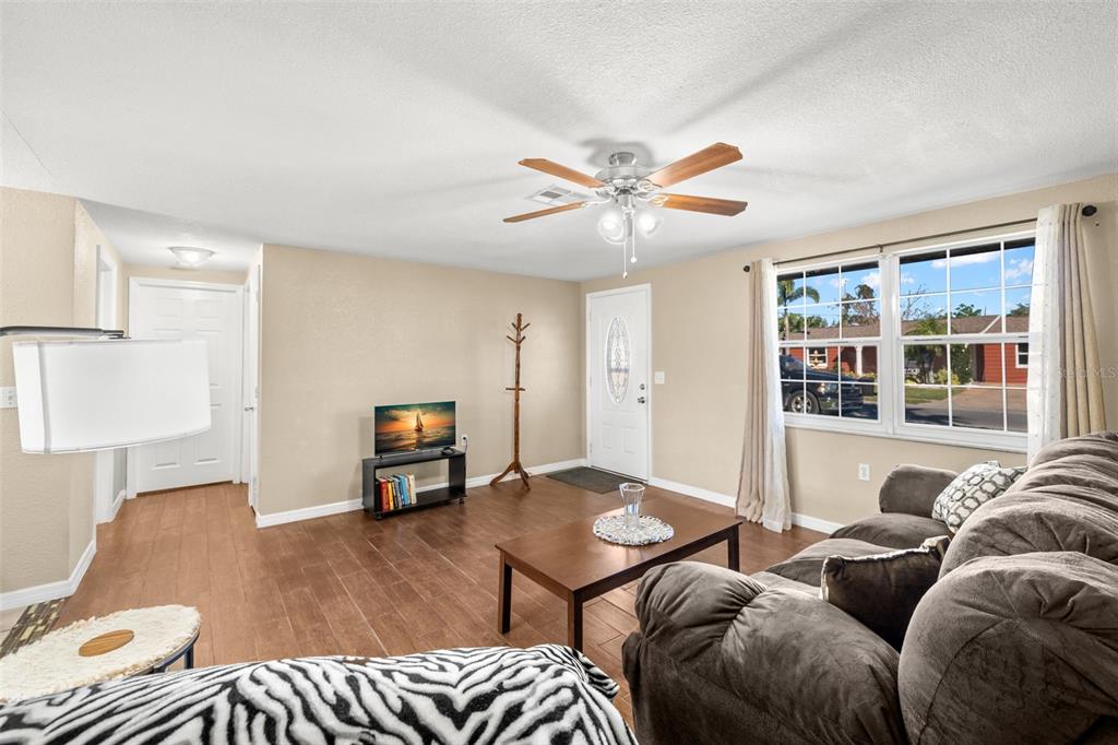 A living room with wood-look tile floors, a ceiling fan, and a brown sofa — 4642 EASTWOOD LANE, HOLIDAY, FL
