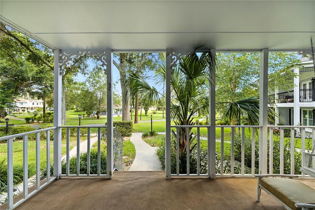 A covered porch with white railings and decorative brackets overlooks a grassy residential lawn — 9951 SW 88TH COURT ROAD UNIT B, OCALA, FL