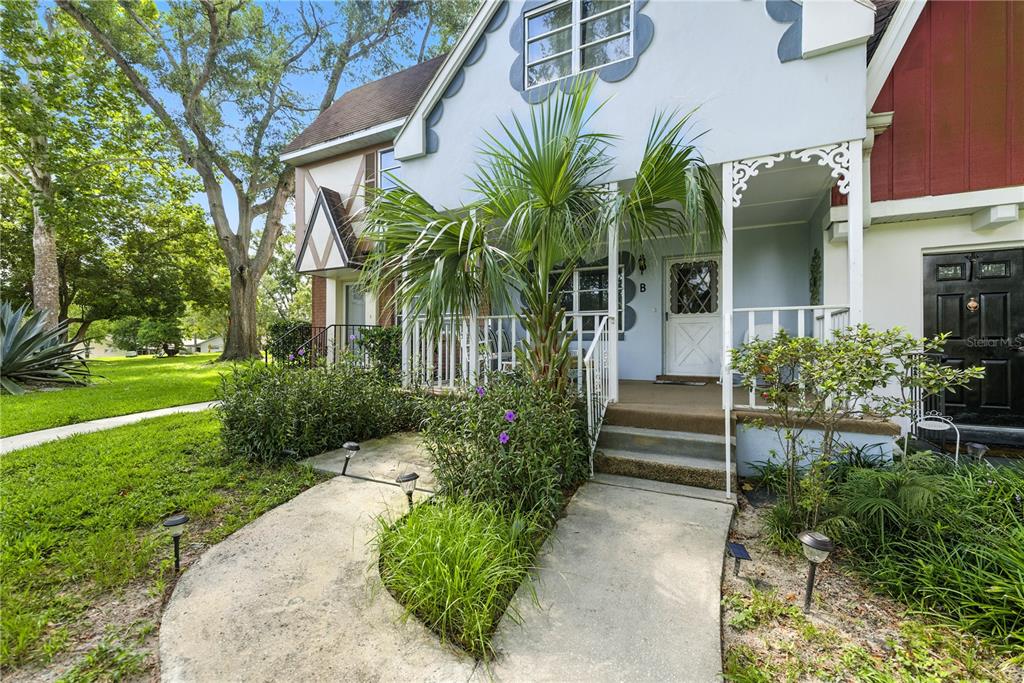 A light blue two-story townhouse exterior features a front porch, a palm tree, and landscaping — 9951 SW 88TH COURT ROAD UNIT B, OCALA, FL