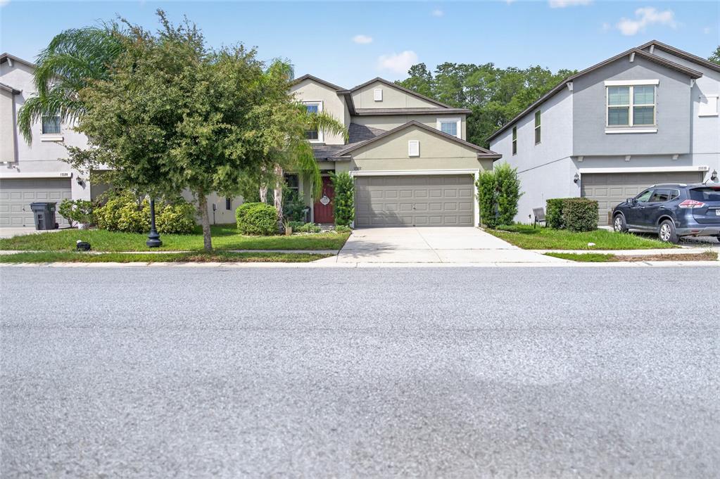 A red front door with a welcome sign sits beside a garage and landscaping — 13322 MARBLE SANDS COURT, HUDSON, FL