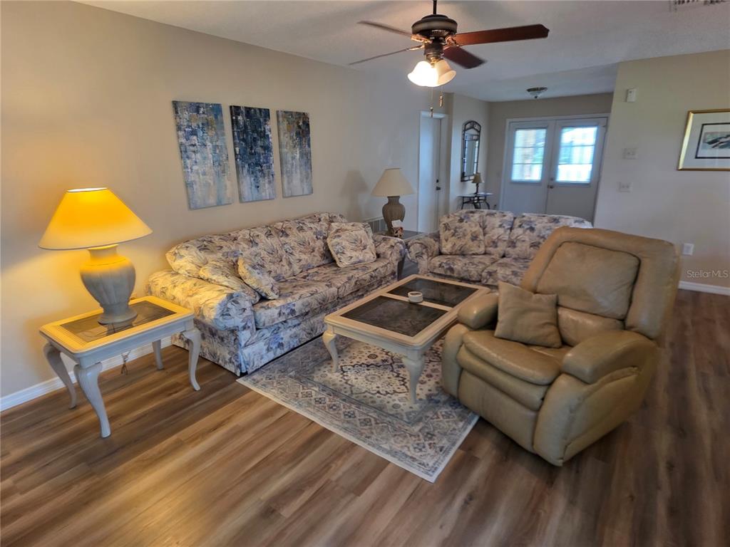 A living room features floral sofas, a leather recliner, a coffee table, and wood-look flooring — 6234 GLEN EAGLES COURT, SPRING HILL, FL