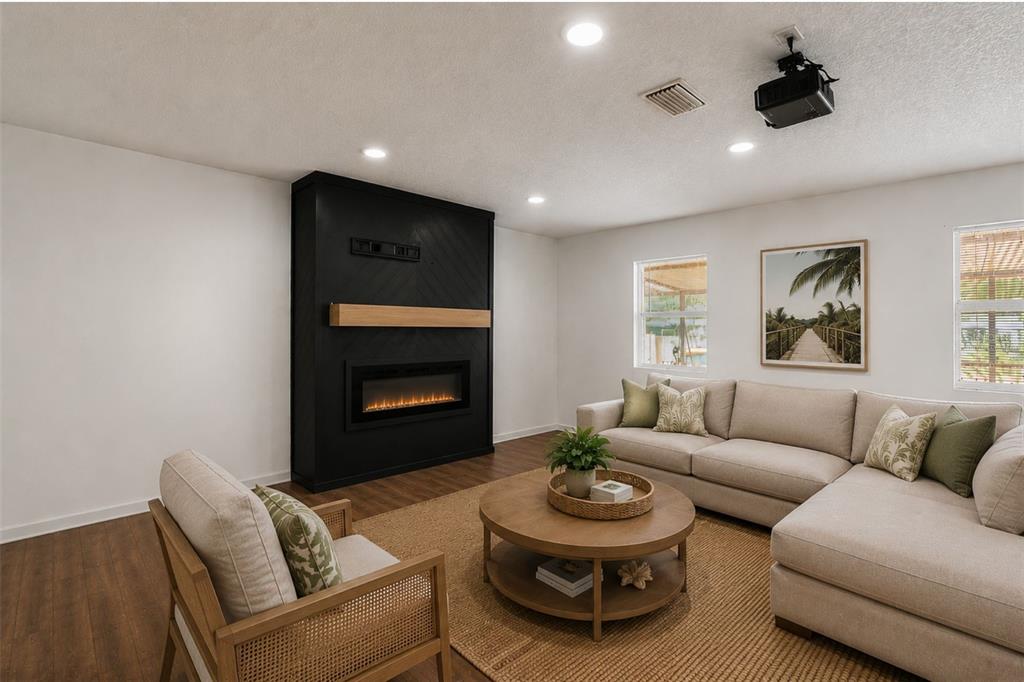 A living room features a black fireplace wall, a sectional sofa, and a round coffee table — 1124 GRANT AVENUE, MOUNT DORA, FL