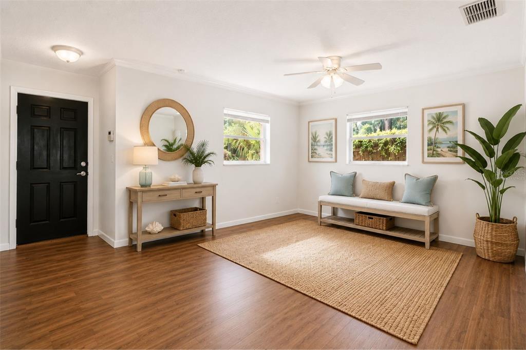 A bright entryway features wood-look flooring, a console table, a bench, and a black door — 1124 GRANT AVENUE, MOUNT DORA, FL