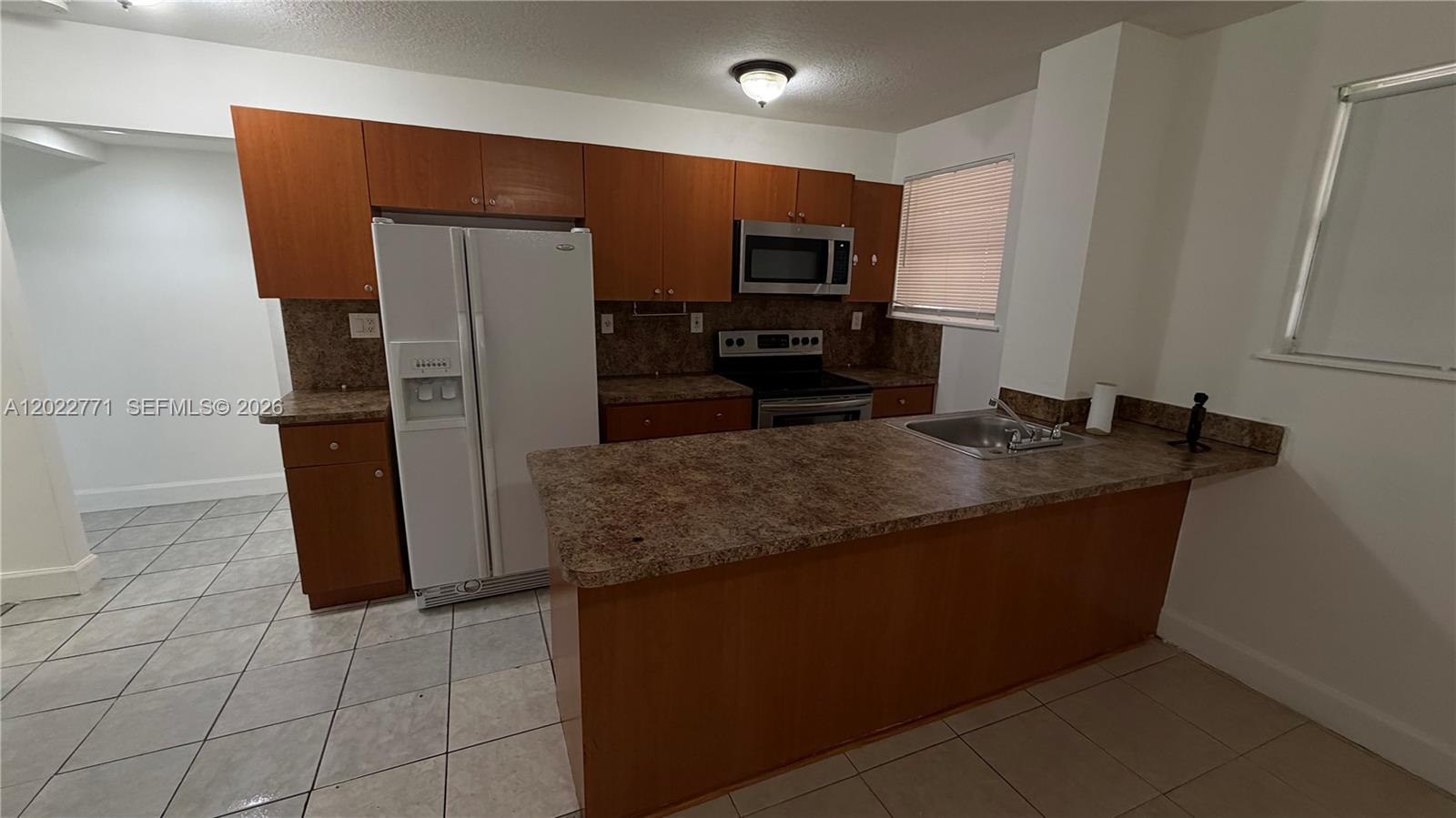 A kitchen features wood cabinets, a white refrigerator, a stove, and a laminate countertop — 14180 NW 22nd Ave # 1, Opa-Locka FL 33054, OPA-LOCKA, FL