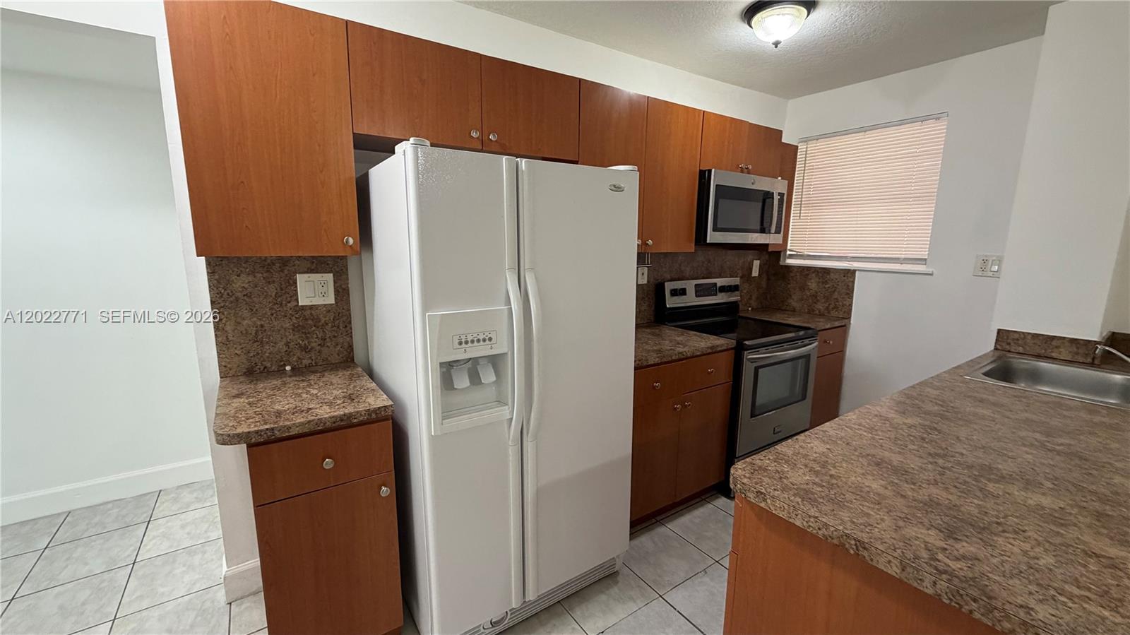 A kitchen features wood cabinets, laminate countertops, a white refrigerator, and stainless steel appliances — 14180 NW 22nd Ave # 1, Opa-Locka FL 33054, OPA-LOCKA, FL