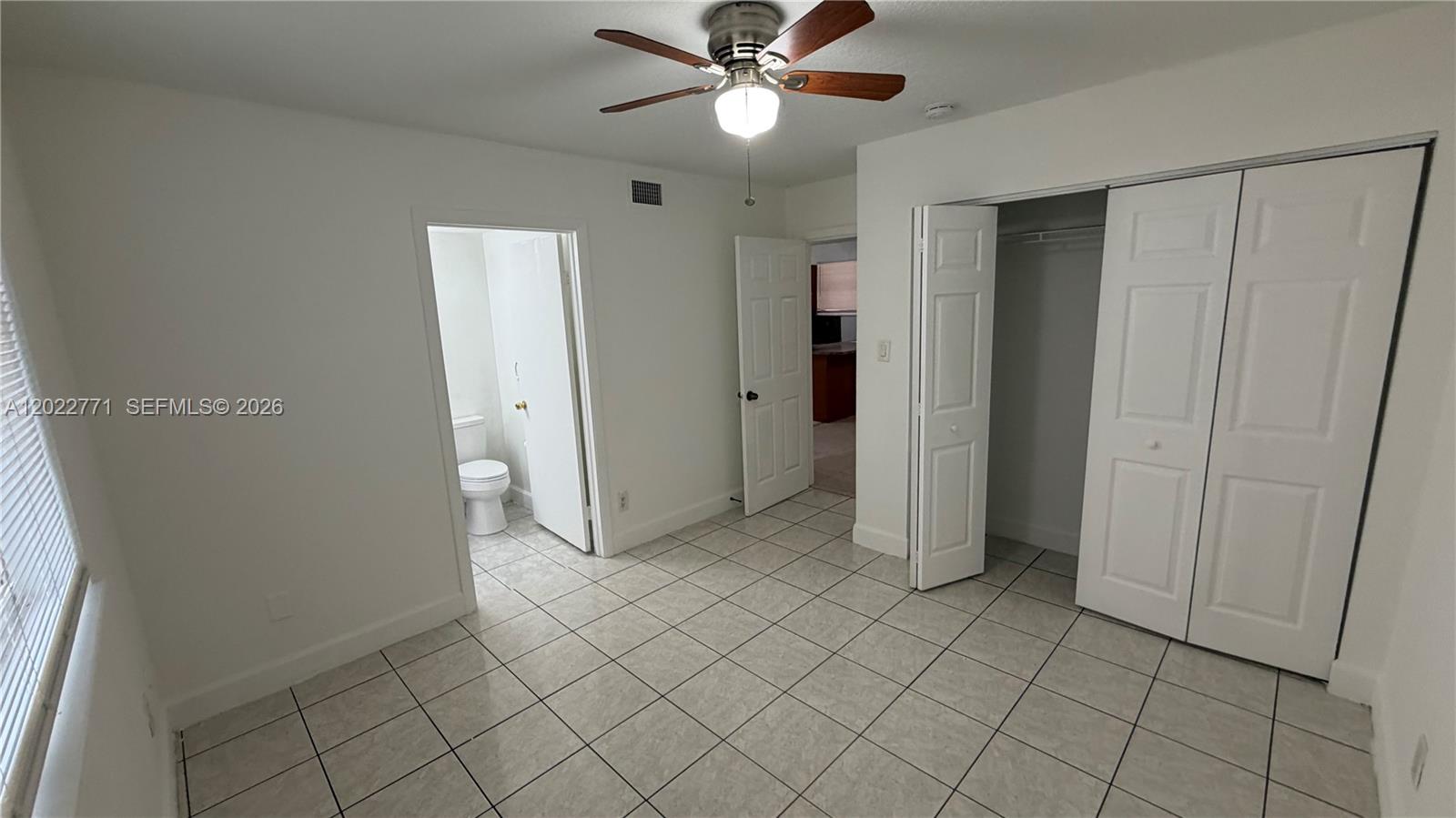 A bedroom with white walls, tile flooring, a ceiling fan, and an attached bathroom — 14180 NW 22nd Ave # 1, Opa-Locka FL 33054, OPA-LOCKA, FL