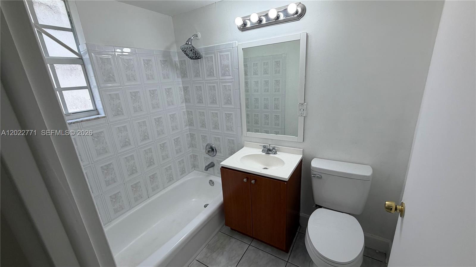 A small bathroom features a white bathtub, a wood vanity, and a toilet — 14180 NW 22nd Ave # 1, Opa-Locka FL 33054, OPA-LOCKA, FL