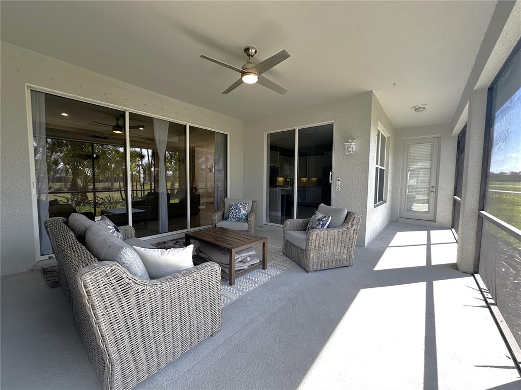 A covered patio features wicker furniture, a ceiling fan, and sliding glass doors — 25191 KEYGRASS COURT, PUNTA GORDA, FL