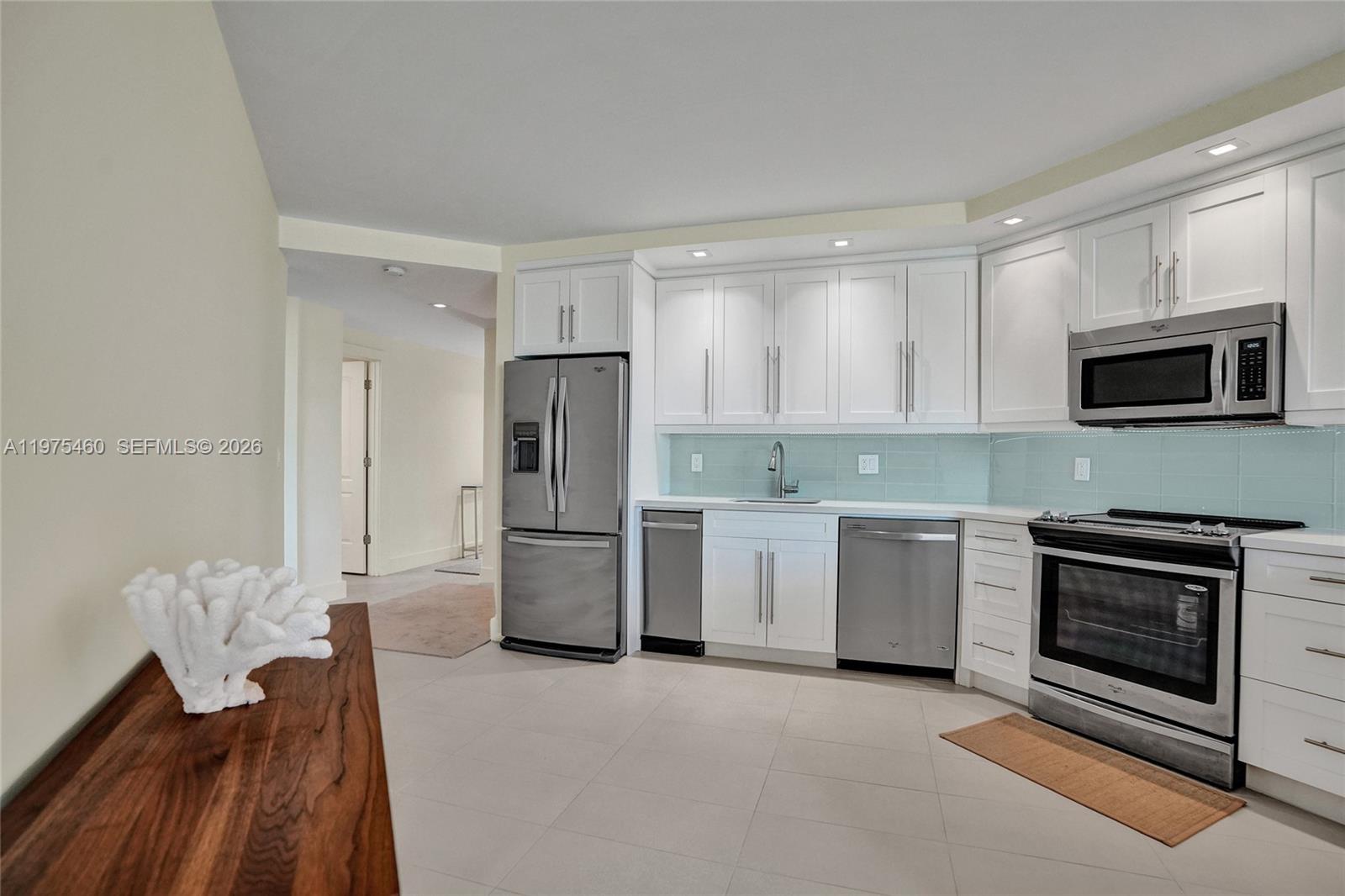 A modern kitchen features white cabinetry, stainless steel appliances, and a light blue backsplash — 1936 S Ocean # 21D, Hallandale Beach FL 33009, HALLANDALE BEACH, FL