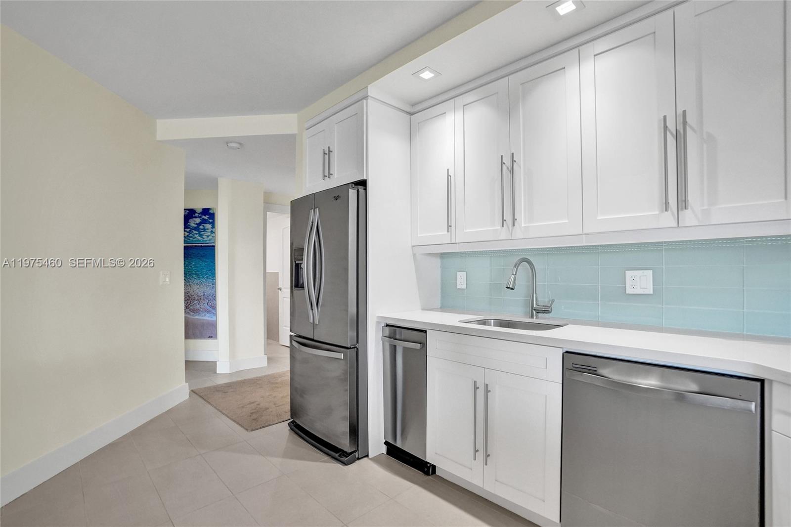 A kitchen features white cabinets, stainless steel appliances, and a light blue tiled backsplash — 1936 S Ocean # 21D, Hallandale Beach FL 33009, HALLANDALE BEACH, FL