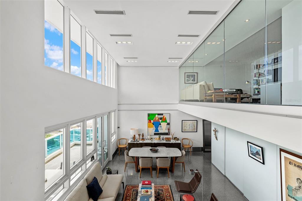 A two-story living and dining area features floor-to-ceiling windows, a glass-enclosed loft, and polished floors — 550 AVENIDA CONSTITUCION UNIT PH-1608, SAN JUAN, PR
