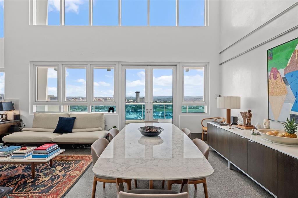 A bright living and dining area features floor-to-ceiling windows, a marble table, and city views — 550 AVENIDA CONSTITUCION UNIT PH-1608, SAN JUAN, PR