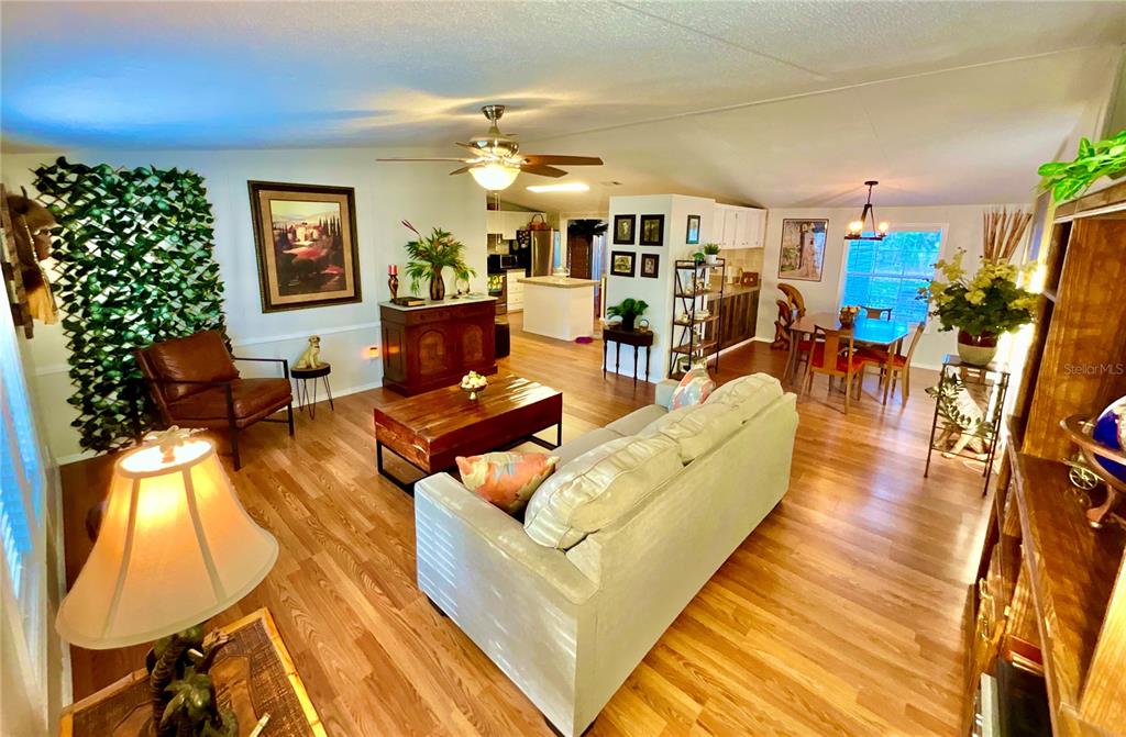A living room with wood-look flooring, a ceiling fan, and an open dining area — 129 CRYSTAL LAKE DRIVE, MELROSE, FL