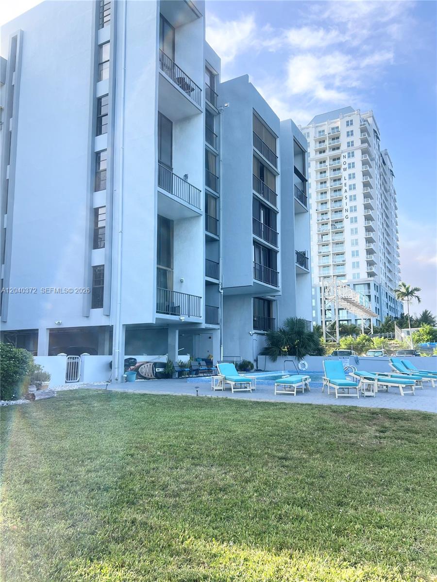 An exterior view of a multi-story apartment building with a swimming pool and lounge chairs — 7899 NE Bayshore Ct # 6A, Miami FL 33138, MIAMI, FL