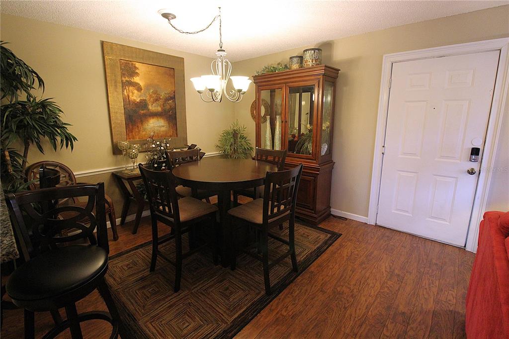 A dining area features a round wooden table, four chairs, a hutch, and wood flooring — 4009 CROCKERS LAKE BOULEVARD UNIT 11, SARASOTA, FL