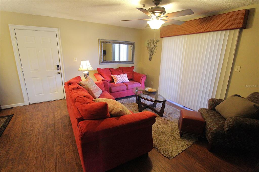 A living room features red sofas, a glass coffee table, and wood-look flooring — 4009 CROCKERS LAKE BOULEVARD UNIT 11, SARASOTA, FL