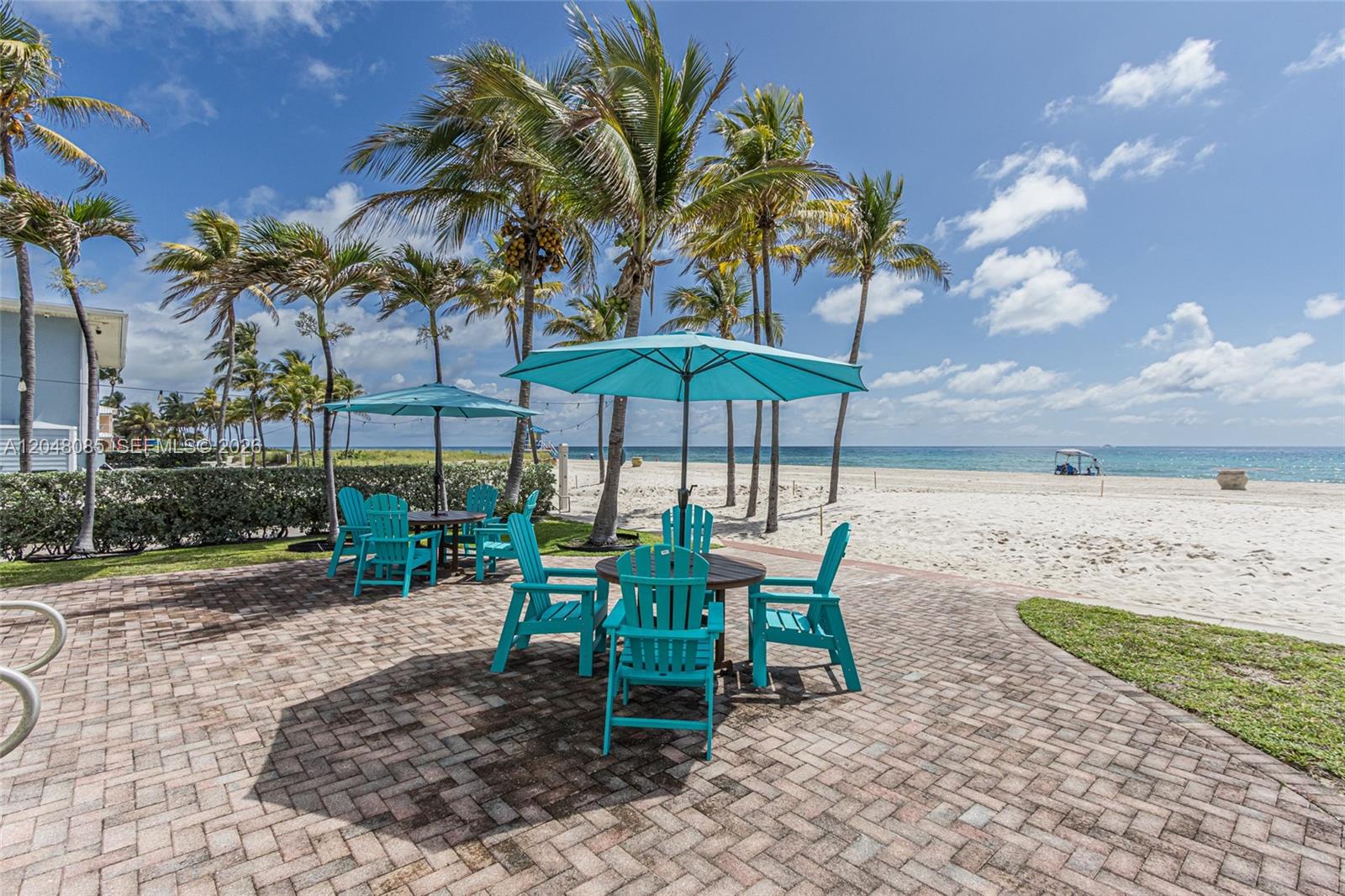 A brick patio features two sets of turquoise chairs and umbrellas overlooking a sandy beach — 1801 S Surf Rd # 2G, Hollywood FL 33019, HOLLYWOOD, FL