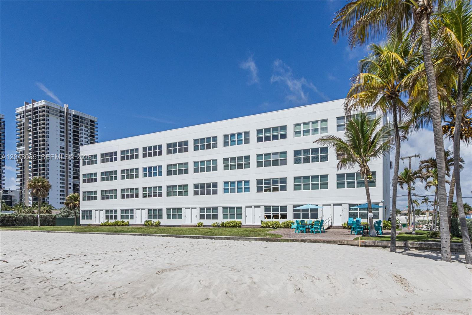 A multi-story white apartment building sits directly on a sandy beach with palm trees — 1801 S Surf Rd # 2G, Hollywood FL 33019, HOLLYWOOD, FL