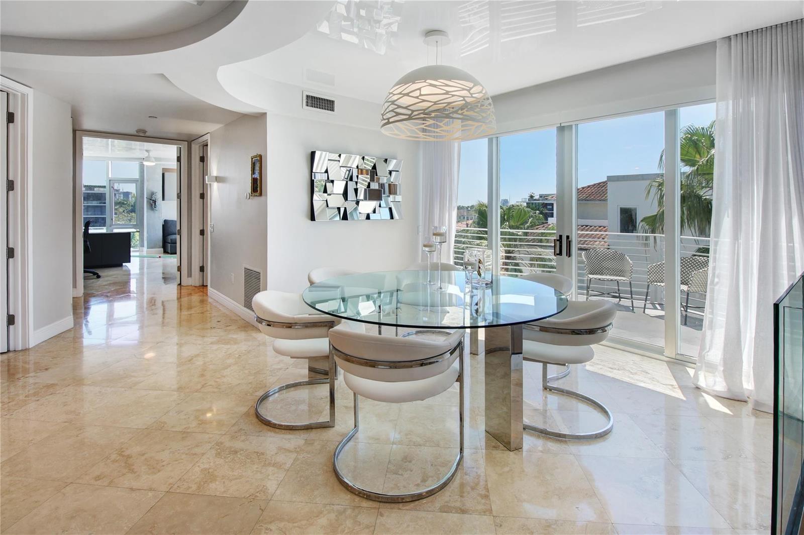 A dining area features a glass-topped table, white chairs, and large sliding doors to a balcony — 301 Hendricks Isle # 7, Fort Lauderdale FL 33301, FORT LAUDERDALE, FL