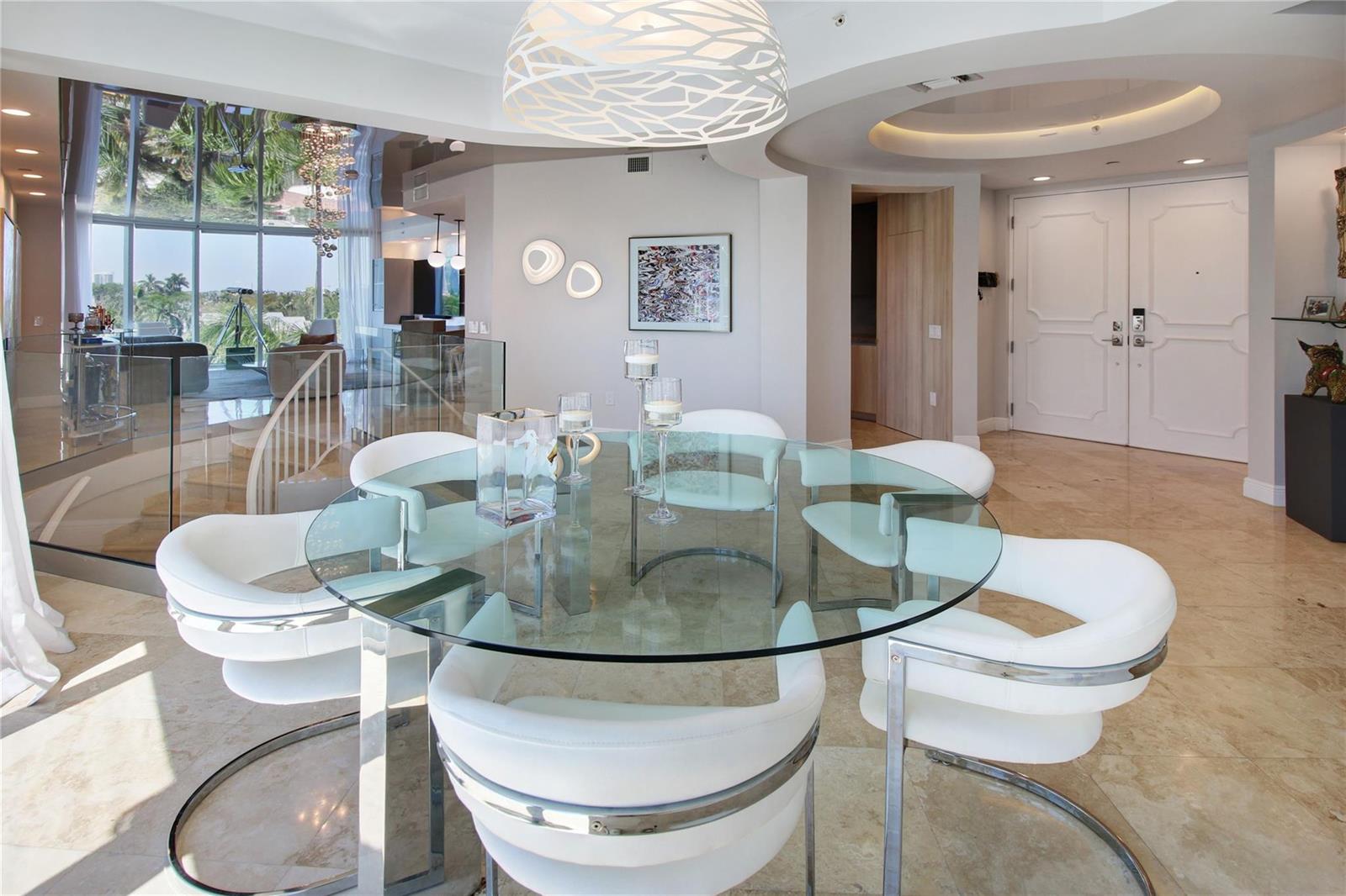 A dining room features a round glass table, white chairs, and a modern pendant light — 301 Hendricks Isle # 7, Fort Lauderdale FL 33301, FORT LAUDERDALE, FL