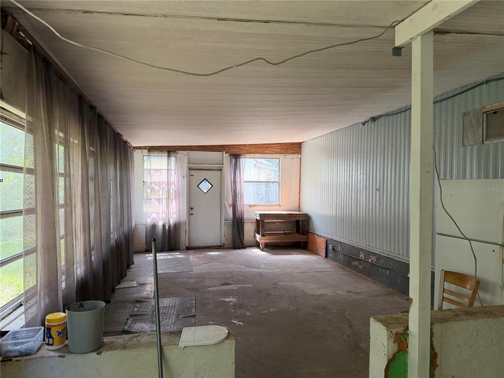 An enclosed porch features a concrete floor, metal wall paneling, and a wooden workbench — 196 ROBINHOOD DRIVE, DELAND, FL
