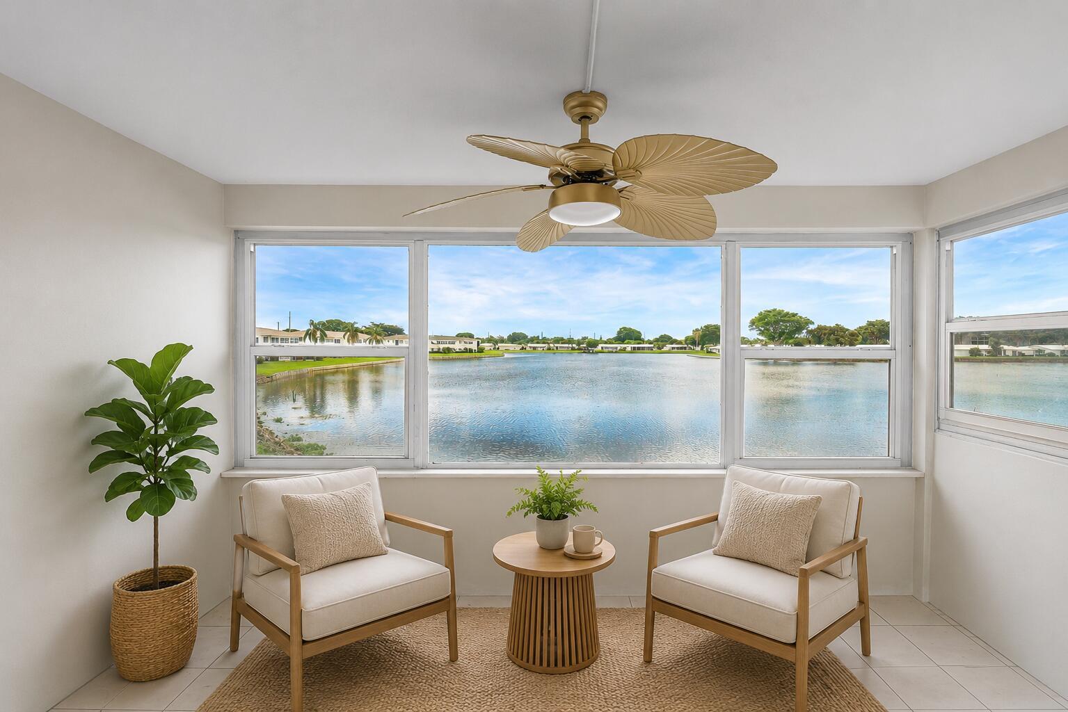 A sunroom features two armchairs, a small table, and a ceiling fan overlooking a lake — 1116 Lake Terrace # 207, Boynton Beach FL 33426, BOYNTON BEACH, FL