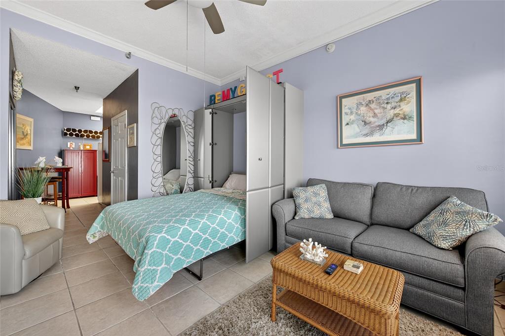 A living room features a gray sofa, a pull-down bed, and tile flooring — 701 S ATLANTIC AVENUE UNIT 111, DAYTONA BEACH, FL