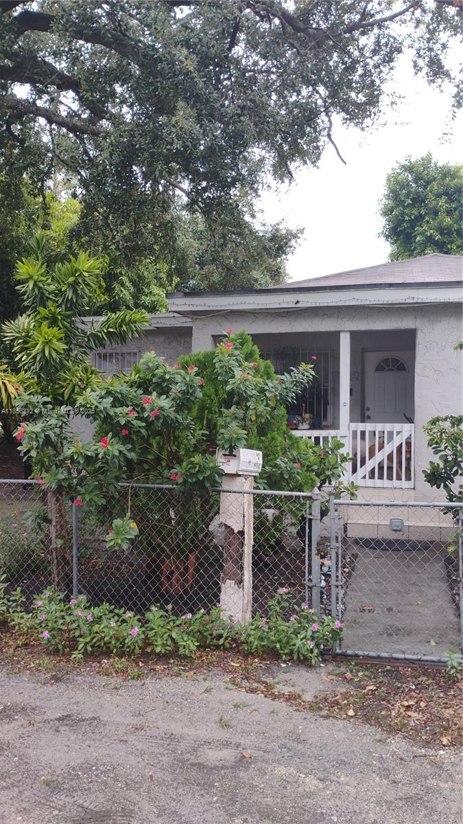 A single-story house with a white porch, chain-link fence, and a mailbox on a post — 7312 NW 17th Ct, Miami FL 33147, MIAMI, FL