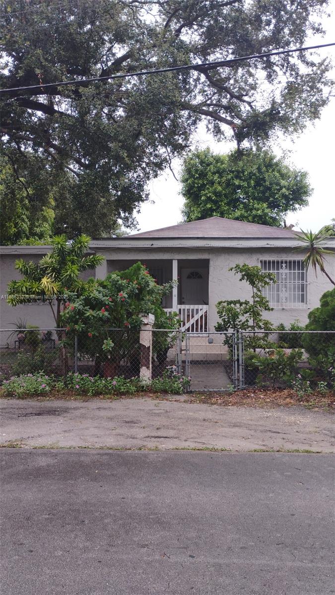 A single-story house with a gray stucco exterior, a front porch, and a chain-link fence — 7312 NW 17th Ct, Miami FL 33147, MIAMI, FL