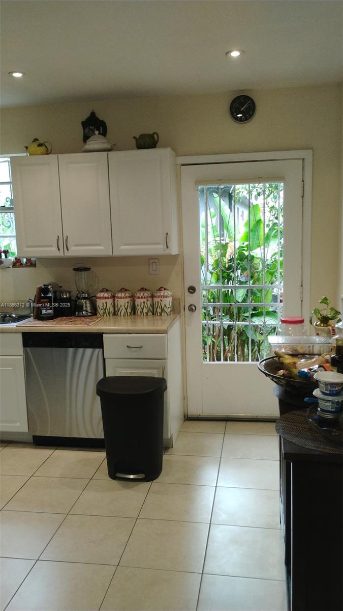A kitchen features white cabinets, stainless steel appliances, tile flooring, and a glass-paned exterior door — 7312 NW 17th Ct, Miami FL 33147, MIAMI, FL