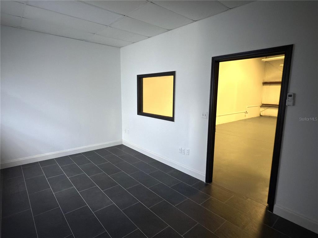 A room with dark tile flooring, a square window, and a doorway leading to a storage area — 5475 WILLIAMSBURG DRIVE, PUNTA GORDA, FL
