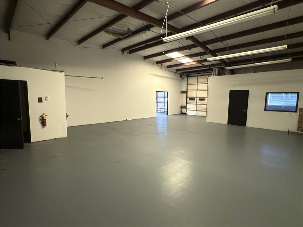 An empty warehouse space features a gray concrete floor, white walls, and exposed ceiling beams — 5475 WILLIAMSBURG DRIVE, PUNTA GORDA, FL