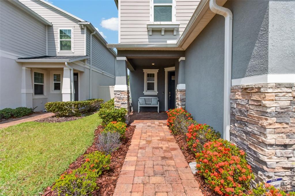 A paved walkway leads to the covered front entrance of a two-story home with stone accents — 8114 ARTISAN CIRCLE, SEMINOLE, FL