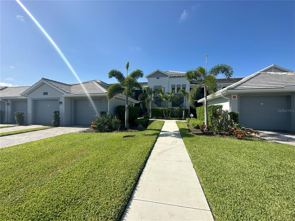A sidewalk leads toward the entrance of a multi-unit residential building with attached garages — 14040 HERITAGE LANDING BOULEVARD UNIT 113, PUNTA GORDA, FL