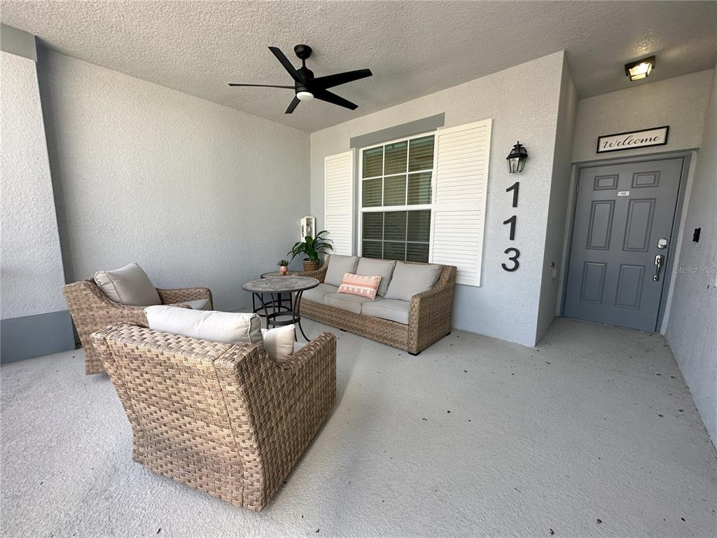 A covered patio features wicker furniture, a ceiling fan, and a gray front door — 14040 HERITAGE LANDING BOULEVARD UNIT 113, PUNTA GORDA, FL