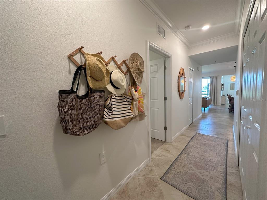A hallway features a wooden wall-mounted coat rack with hats and bags, tile flooring, and doors — 14040 HERITAGE LANDING BOULEVARD UNIT 113, PUNTA GORDA, FL