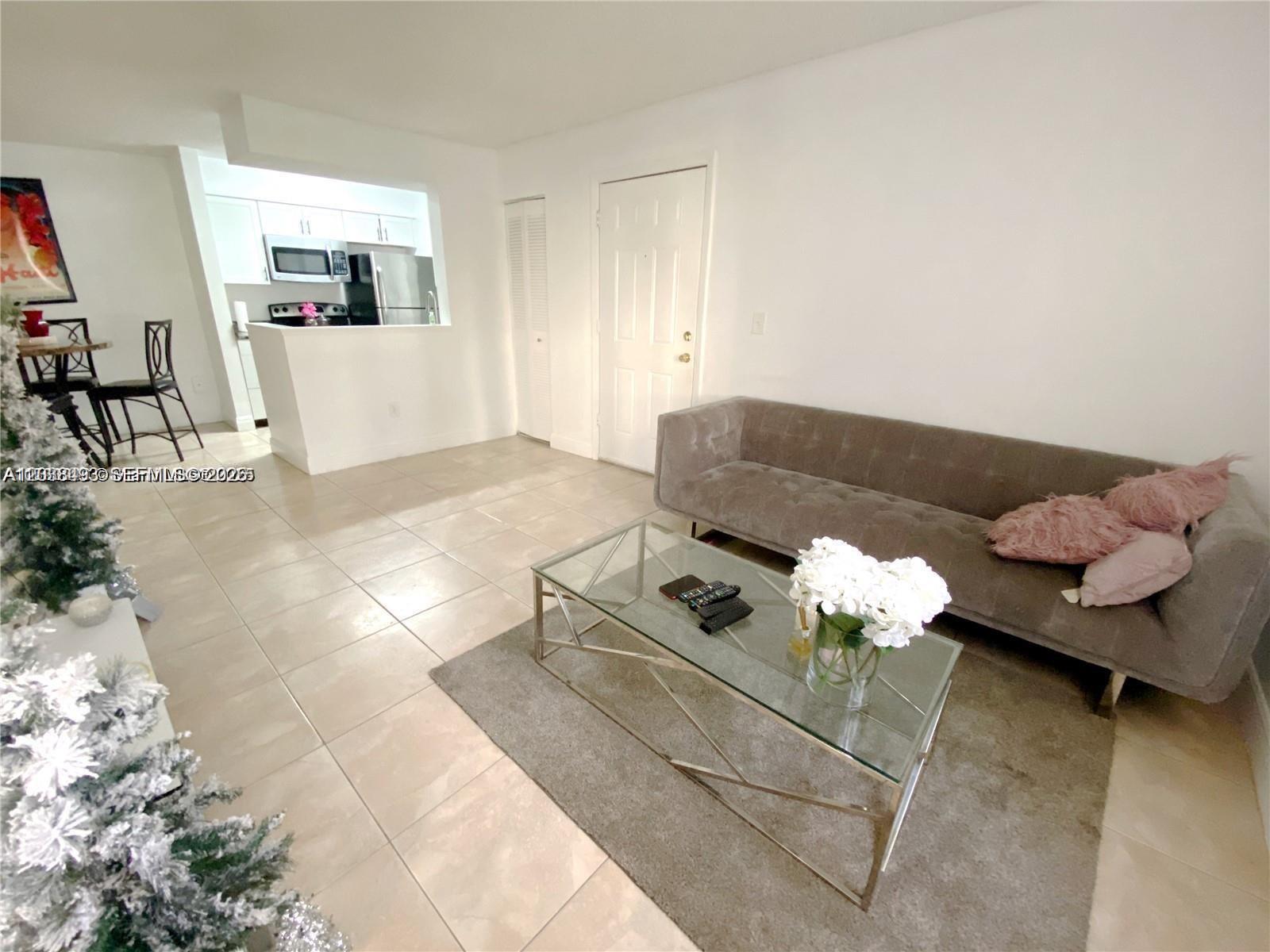 A living room with tile floors, a gray sofa, and an adjacent kitchen area — 1257 SW 46th Ave # 1801, Pompano Beach FL 33069, POMPANO BEACH, FL