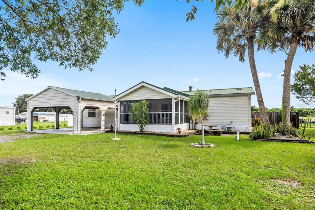 A single-story home with a metal roof, attached carport, and a screened-in porch — 8945 SE 57TH DRIVE, OKEECHOBEE, FL