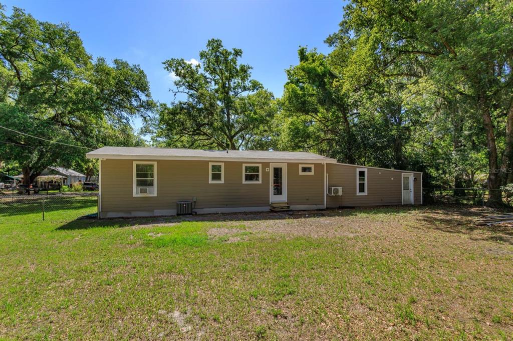 The exterior of a single-story tan house with a yard and surrounding trees — 2820 MAGNOLIA AVENUE, SANFORD, FL