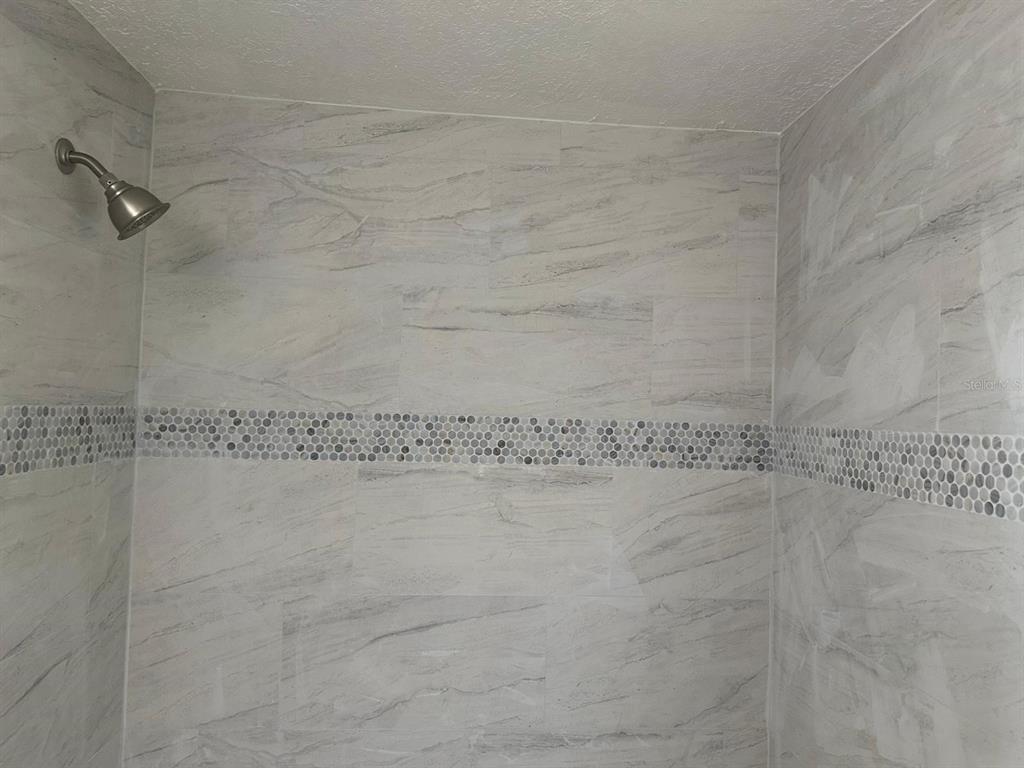 A shower stall features light gray marble-look wall tiles with a horizontal mosaic accent strip — 724 GROVE AVENUE, ORLANDO, FL