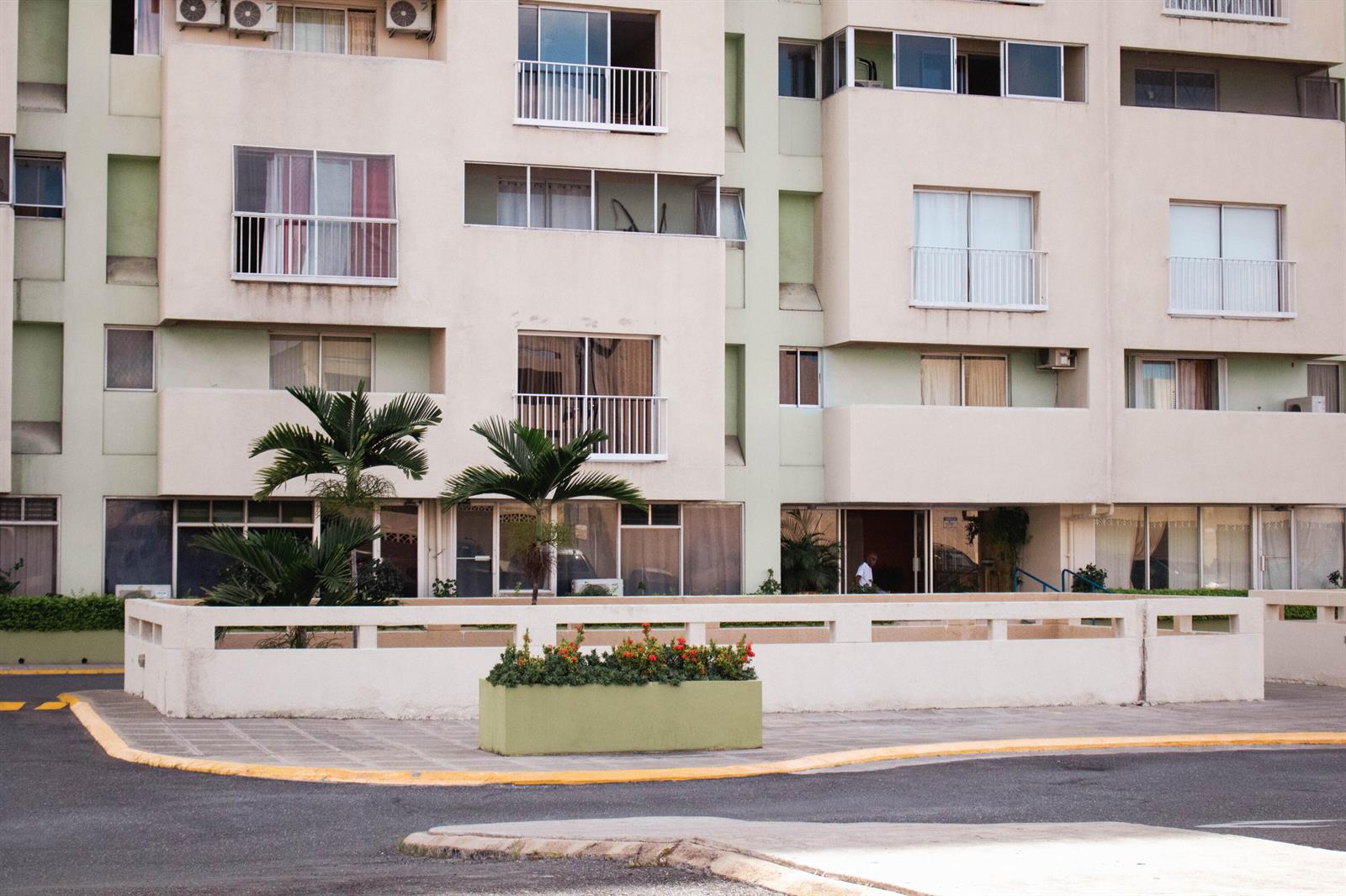 A multi-story apartment building features balconies, large windows, and a low concrete wall with planters — 8 Ocean Blvd Kingston Jamaica Boulevard, FL