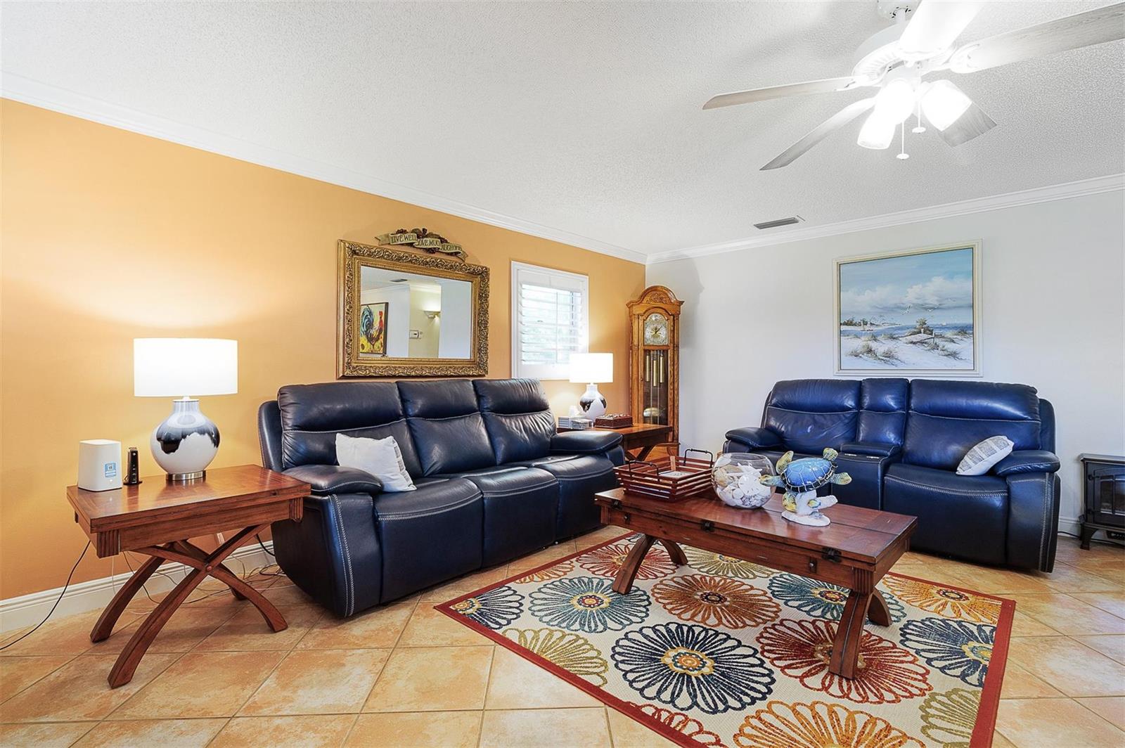 A living room features two navy blue leather sofas, a wooden coffee table, and tile flooring — 63 Woodland Drive, Vero Beach FL 32962, VERO BEACH, FL