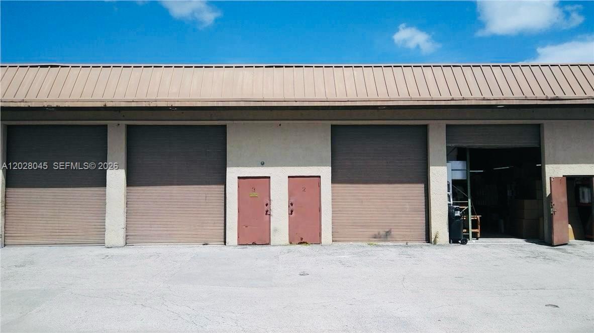 The exterior of a commercial warehouse building features multiple roll-up doors and two metal entry doors — 1901 NW 32nd St # 6, Pompano Beach FL 33064, POMPANO BEACH, FL
